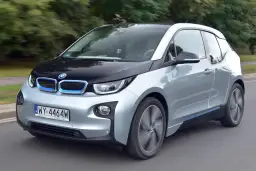 Srebrno-czarny BMW i3, elektryczny samochód, jedzie po drodze.