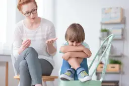 Nauczycielka wspomagająca rozmawia z chłopcem, który wygląda na smutnego. Jej pensum obejmuje wsparcie dzieci w trudnych chwilach.