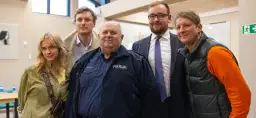 Grupa osób, w tym policjant, pozuje do zdjęcia. Wyglądają, jakby reżyser u pana boga za piecem ustawił ich do tej sceny.