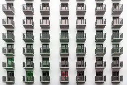 Rząd balkonów na białej fasadzie budynku mieszkalnego.