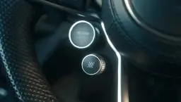 Przycisk z szachownicą na kierownicy, gotowy do aktywacji launch control. Obok przycisk Drive Select.