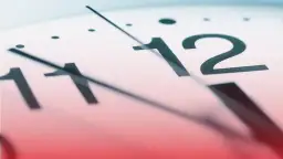 Zbliżenie na tarczę zegara, wskazówki zbliżają się do godziny 12. Ile godzin pracy jeszcze zostało?