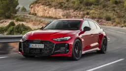 Czerwone Audi RS 7 pokonuje zakręt na malowniczej, górskiej drodze.