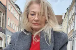 Szafiarka Dorka, ile ma lat? Kobieta w szarym płaszczu i czerwonym swetrze na tle kamienic.