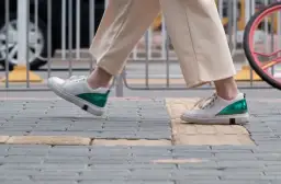 Białe sneakersy z zielonym akcentem na pięcie, idealne na spacer. Zastanawiasz się, jaki rozmiar buta francuski a polski wybrać?