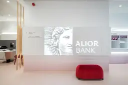 Nowoczesne wnętrze oddziału Alior Bank z logo banku, grafiką i czerwonym pufem.