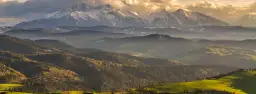 Piękne polskie góry, gdzie jechać? Tatry ośnieżone, a u ich podnóża zielone wzgórza i lasy w jesiennych barwach.