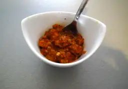 Czerwona pasta curry w białej miseczce z łyżką.