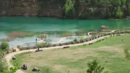Turkusowe jezioro z drewnianą kładką i altanką, idealne na jednodniową wycieczkę. Ciekawe miejsca do 50 km od Katowic.
