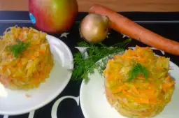 Dwie porcje surówki z kiszonej kapusty z jabłkiem, marchewką i koprem. Obok składniki: jabłko, cebula, marchewka.