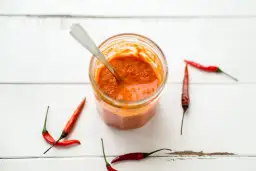 Tarro de salsa piri piri casera con chiles rojos alrededor. ¡Lista para dar sabor!