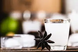 Mętny arak w szklance, obok gwiazdka anyżu i kostki lodu.
