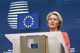 Ursula von der Leyen przemawia na tle flagi UE i logo Komisji Europejskiej.