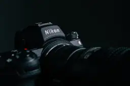 Ciemne zdjęcie aparatu Nikon z obiektywem, z widocznym logo.