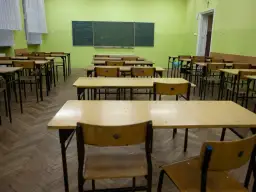 Puste ławki w sali lekcyjnej, czekające na powrót uczniów do szkoły po świętach wielkanocnych.