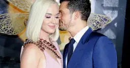 Katy Perry i Orlando Bloom w czułym uścisku. Ona w różowej sukni i masywnym naszyjniku, on w granatowym garniturze.