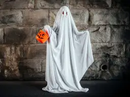 Dziecko w przebraniu na Halloween DIY jako duch, trzymające pomarańczową dynię na cukierki.