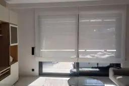 Eleganckie rolety elektryczne wewnętrzne na baterie, wykonane z półprzezroczystego materiału, tworzą przytulną atmosferę w nowoczesnym salonie.