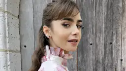 Mujer con peinado y maquillaje impecables, destacando el laminado de cejas. Viste una blusa con volantes y estampado floral.