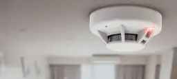 Czujnik gazu ziemnego zamontowany na suficie. Czerwona dioda sygnalizuje alarm.