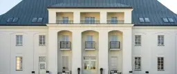 Elegancki Zamek Janów Podlaski, z białymi fasadami i ciemnym dachem, zachęca do odwiedzin. Opinie gości potwierdzają jego urok.