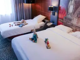 Chambre d'hôtel avec deux lits, jouets et vêtements pour enfants.