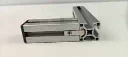 Dwa połączone profile aluminiowe konstrukcyjne tworzą kąt prosty. Widać element łączący z nakrętką.