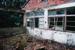 Opuszczony budynek z cegły, zniszczone okna i gruz na ziemi. Zastanawiasz się, gdzie wyrzucić szyby okienne?