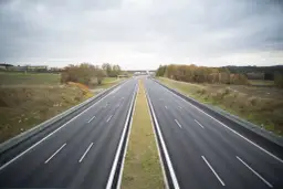 Pusta autostrada w Niemczech, gdzie podróżowanie jest bezpłatne. W oddali widać budynki i jesienne drzewa.