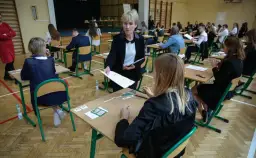 Napięcie w sali gimnastycznej, kiedy rozdawane są arkusze. Uczniowie czekają na wyniki egzaminu ósmoklasisty, a nauczycielka czuwa nad przebiegiem.