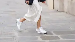 Elegante outfit: vestido blanco satinado con zapatillas deportivas blancas y plateadas.