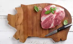 Surowa wieprzowina na desce w kształcie świni. Czy wirus Aujeszkyego w surowej wieprzowinie ginie po ugotowaniu?