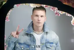 Bart Pniewski, młody mężczyzna w jeansowej kurtce, pozuje z uniesionym znakiem pokoju.