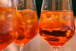 Orzeźwiający aperol bezalkoholowy z lodem w kieliszkach, idealny na letnie popołudnie.