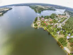 Widok z lotu ptaka na zalew zemborzycki z żaglówkami, domkami i wieżą widokową.
