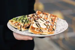 Pyszne gofry belgijskie z bananem i kiwi, polane czekoladą. Idealne na śniadanie, gdy masz ochotę na coś słodkiego.
