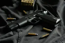 Czarny pistolet GSG-1911 i amunicja na ciemnym tle. Idealny do strzelectwa sportowego.