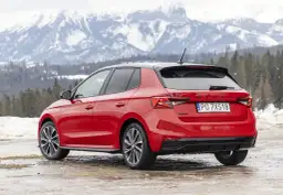 Czerwona Skoda Fabia Monte Carlo z czarnym dachem na tle ośnieżonych gór.
