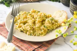 Un plato de bacalao a bras, desmenuzado y mezclado con patatas y perejil, servido con una rebanada de pan.
