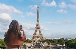 Kobieta robi zdjęcie telefonem ikonicznej wieży Eiffel.