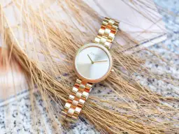 Złoty zegarek damski Calvin Klein na tle kłosów.