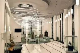 Nowoczesny, przestronny foyer z imponującą, wielopoziomową lampą i szklaną gablotą z rzeźbą.