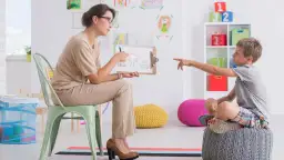 Pedagog szkolny z dzieckiem omawia rysunek domu. Czy po resocjalizacji można być pedagogiem szkolnym?