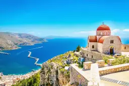 Kamienna cerkiew z czerwoną kopułą na wzgórzu, z widokiem na błękitne morze i port. To musi być najcieplejsza wyspa grecka!