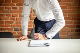 Mężczyzna w białej koszuli podpisuje dokumenty. Co jeśli ZUS nie przyznał świadczenia rehabilitacyjnego?
