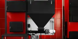 Nowoczesny kocioł co zębiec, z czarnym zasobnikiem i czerwonymi panelami, gotowy do pracy.