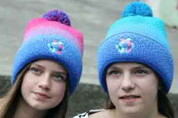 Zwei Mädchen mit bunten Bommelmützen in Blau und Pink.