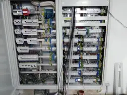 Otwarta skrzynka elektryczna z licznymi przewodami i bezpiecznikami.