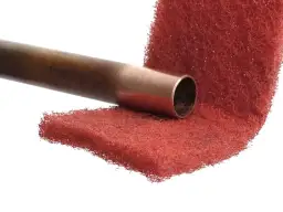 Miedziana rura przygotowana do lutowania aluminium z miedzią, na czerwonej druciance.