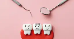 Trzy zęby na różowym tle, dwa uśmiechnięte, jeden smutny z próchnicą. Obok narzędzia dentystyczne. Które zęby są mleczne?